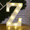 A glowing white letter Z made of LED lights resting on a wooden surface.