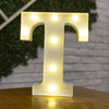 A glowing white letter T made of LED lights resting on a wooden surface.