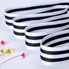 Black and white striped double-sided grosgrain ribbon rolled into several strips