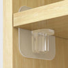 Clear plastic adhesive shelf support pegs mounted on a wooden cabinet shelf.