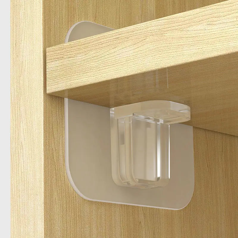 Clear plastic adhesive shelf support pegs mounted on a wooden cabinet shelf.