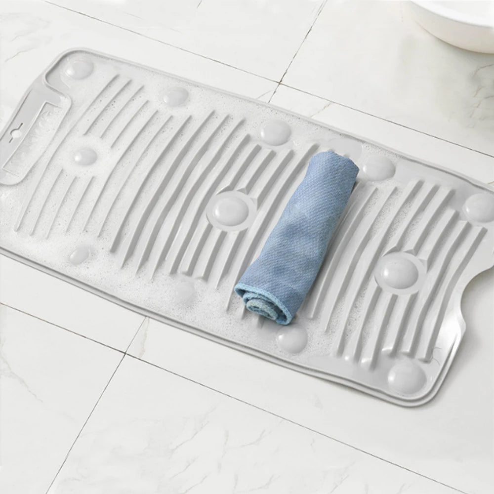 Una tabla de lavado de silicona clara con estrías y agujeros sostiene un paño azul enrollado.