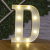A white illuminated letter D made of LED lights resting on a wooden surface.