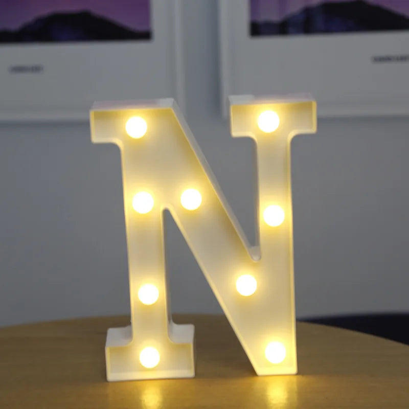 A glowing white letter N made of LED lights sitting on a wooden surface.
