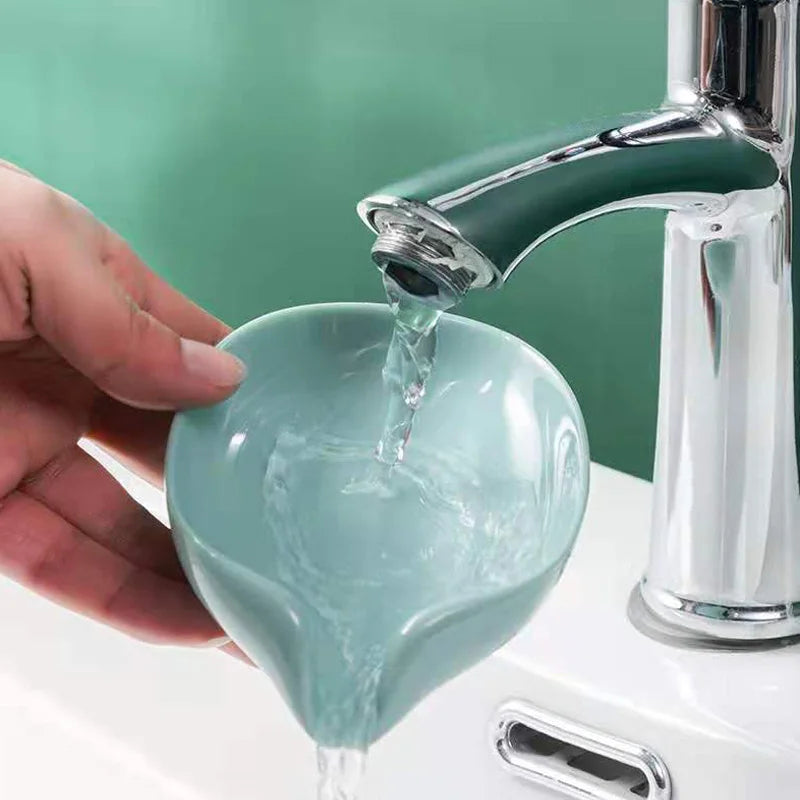 A hand pours water into a leaf-shaped suction cup soap holder with a self-draining tray.