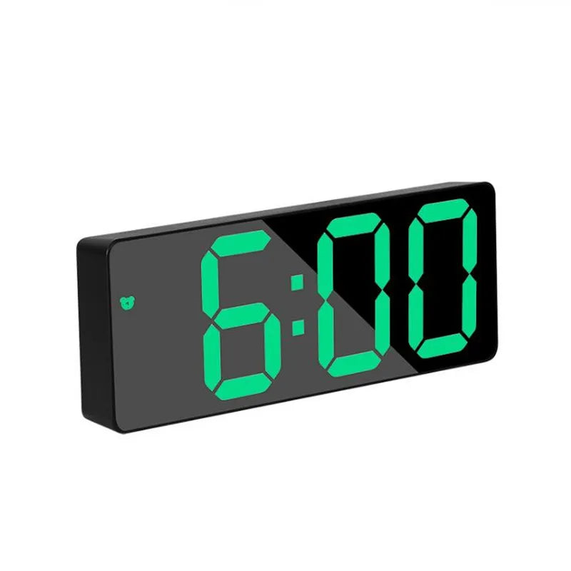A black digital alarm clock displaying 6:00 with bright green LED numbers.