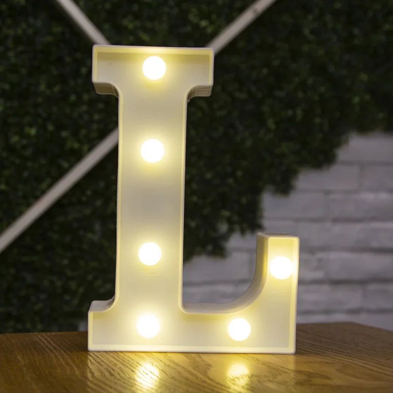 A glowing letter L made of LED lights resting on a wooden surface.