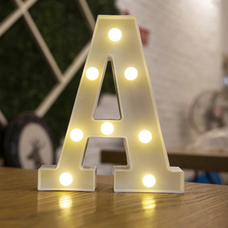 A letter light decoration shaped like the letter A with illuminated bulbs on a wooden surface.