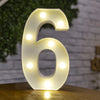 A glowing white number six sign with round LED lights displayed on a wooden surface.