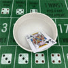 A white bowl holds a playing card on a green felt table with scattered dice and card markings.