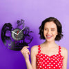 A woman smiling while holding a black vinyl record wall clock with a lion silhouette design against a purple background.
