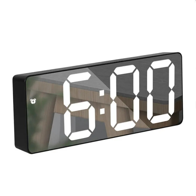 A black digital alarm clock displaying 6:00 on a wooden surface.