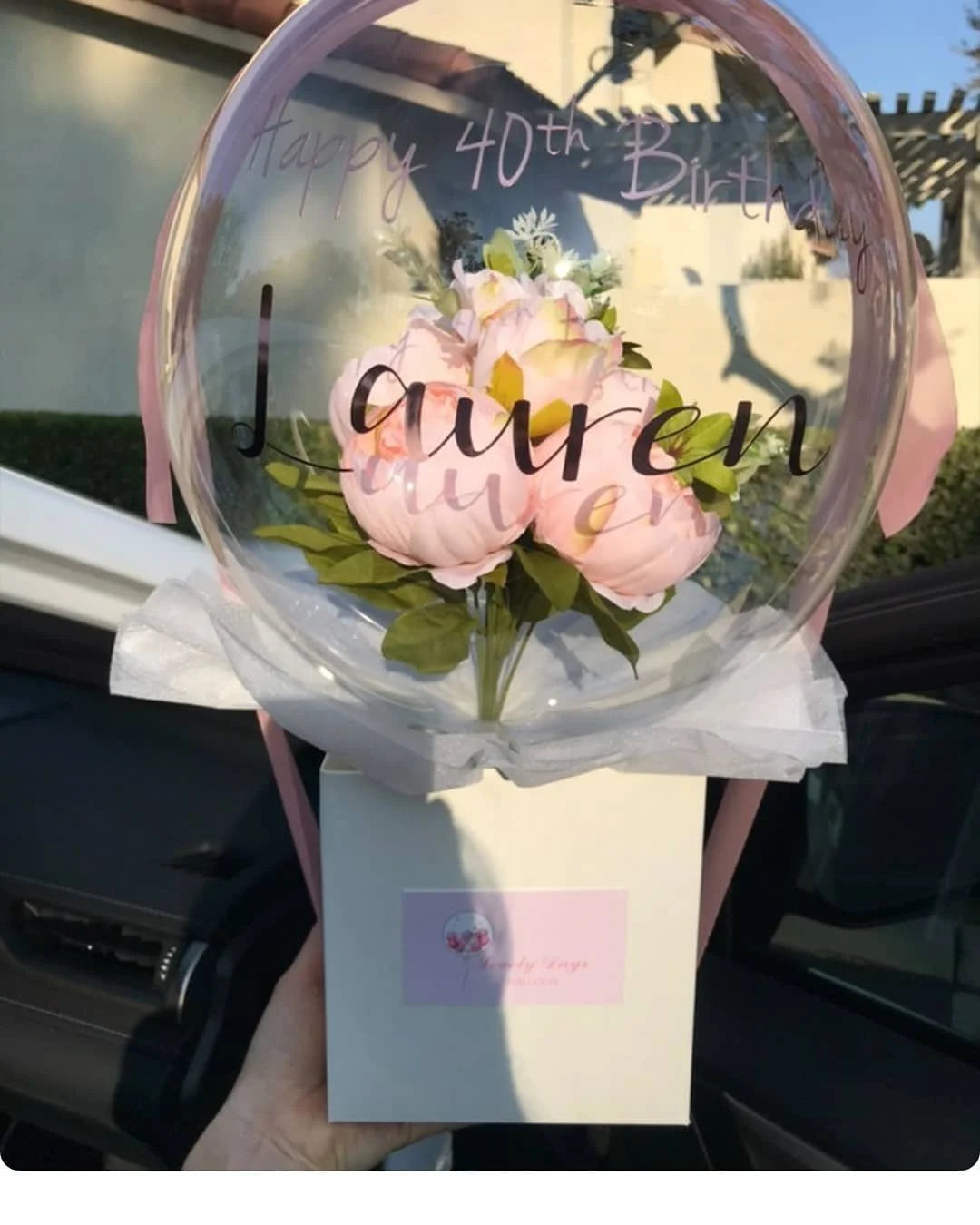 A clear latex balloon is filled with pink flowers and the text Happy 40th Birthday Lauren