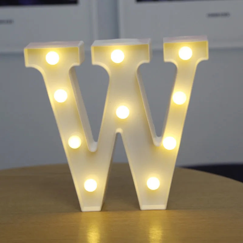 A white alphabet letter W made of LED lights, illuminating the structure with bright yellow light.