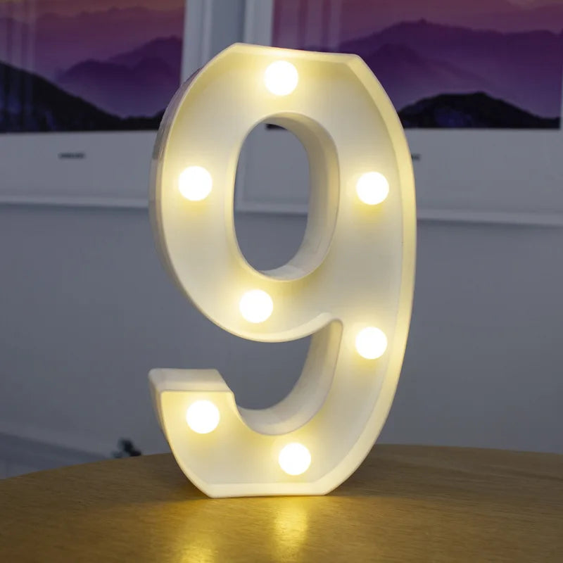 A glowing white number 9 made of acrylic with embedded LED lights sitting on a wooden surface.
