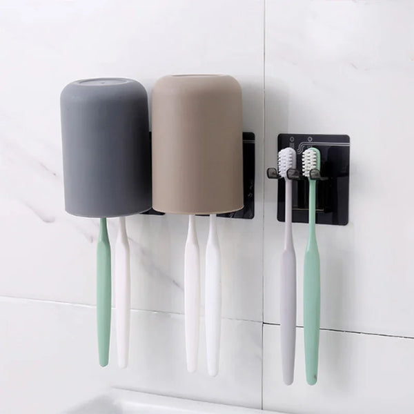 Wall mounted organizer holding a gray cup and three light green toothbrushes.