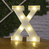A white illuminated letter X made of LED lights resting on a wooden surface.