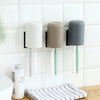 A multi-use wall mounted organizer holding three different colored cups or toothbrushes.