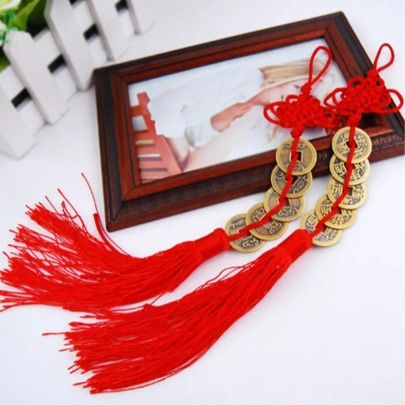 Handmade red knot feng shui coins for prosperity with tassels displayed in a wooden frame.