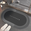 A dark gray non-slip bath mat with the word BATHROOM embossed on it, placed on a bathroom counter.