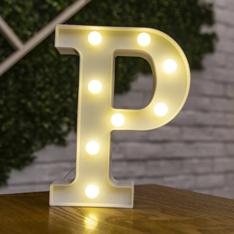 A glowing white plastic letter P made of LED lights resting on a wooden surface.