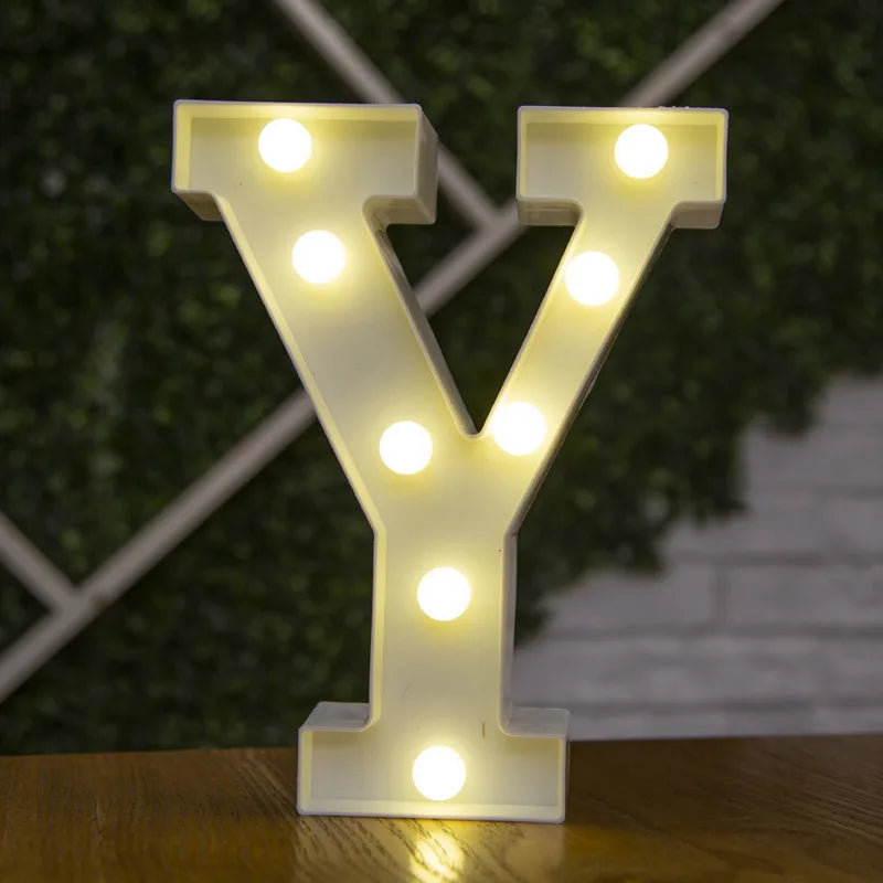A letter Y made of illuminated LED lights standing on a wooden surface.