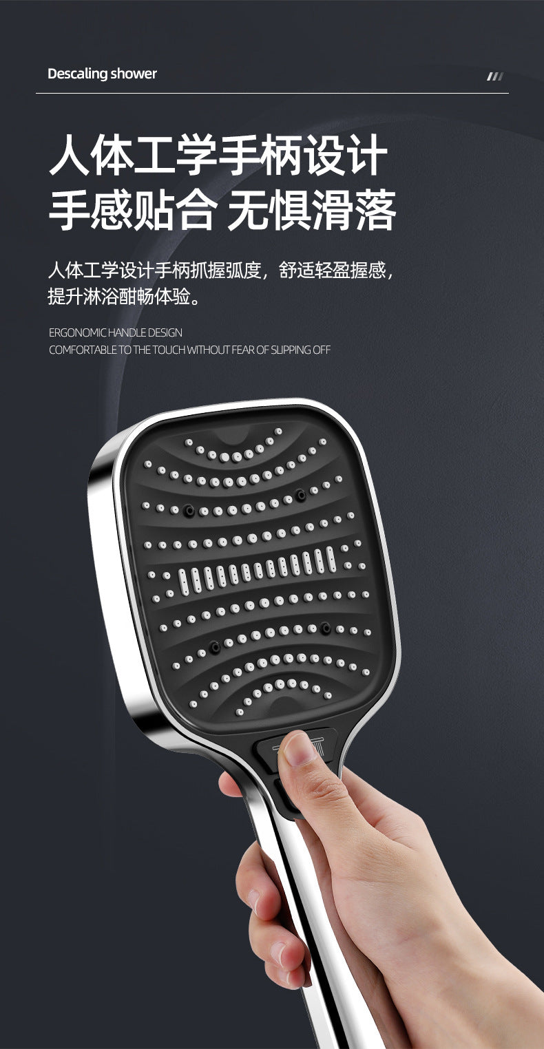 A hand is holding a silver handheld shower head with a textured, perforated nozzle.
