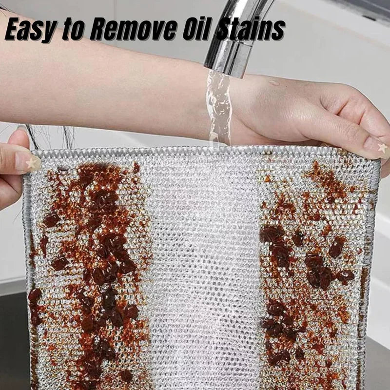 A hand is rinsing oil stains off a thick metal wire cleaning cloth.