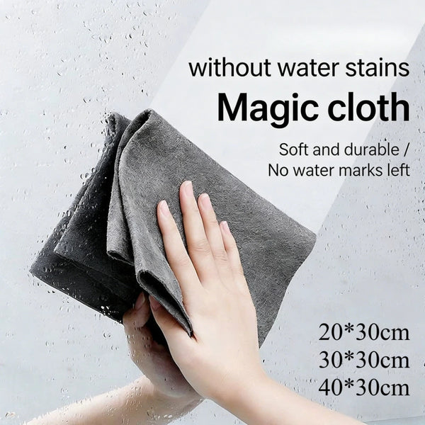 A hand is wiping a glass with a gray microfiber cloth, demonstrating the streak-free cleaning ability.