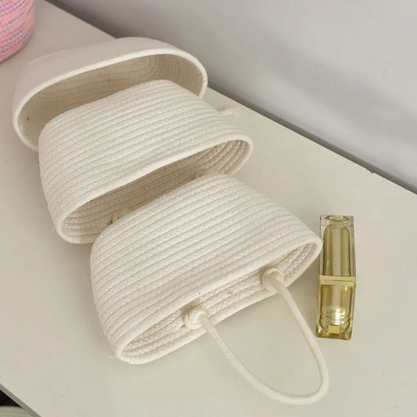 A white handwoven multi-layer storage basket with a handle is shown on a white surface.