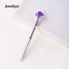 A silver pen with a purple amethyst crystal tip resting on a white surface.