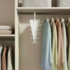 A white multi-hook closet organizer hanger with twelve hooks hanging on a white shelf.
