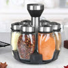 A set of rotating glass spice jars with stainless steel lids displayed on a black rack.