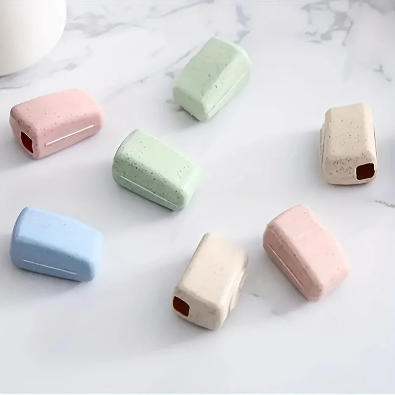A collection of four pastel-colored toothbrush head covers arranged on a white marble surface.