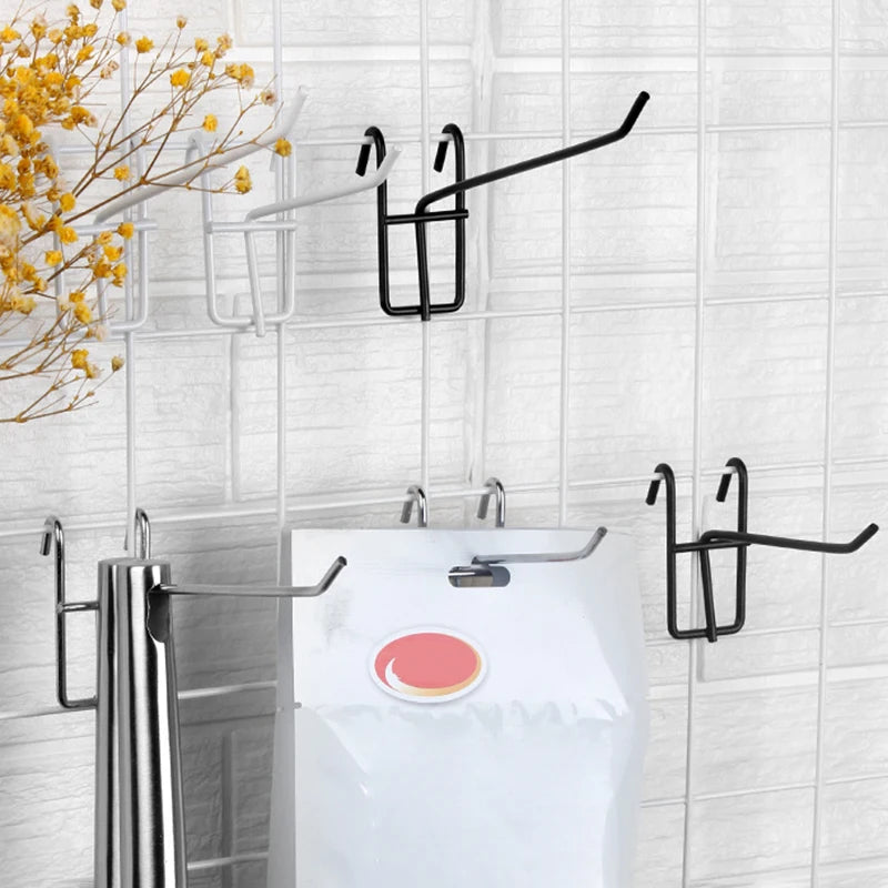 Black heavy-duty mesh grid display hooks mounted on a white tiled wall above a white toilet.