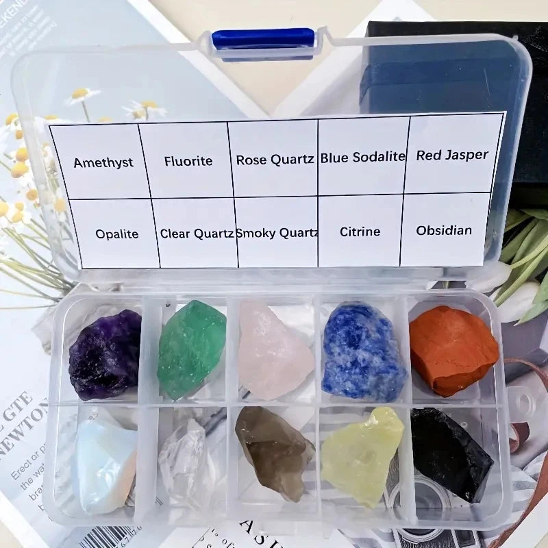 A clear plastic box containing various natural crystal stones including amethyst, fluorite, rose quartz, and jasper.
