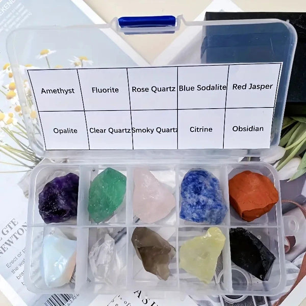 A clear plastic box containing various natural crystal stones including amethyst, fluorite, rose quartz, and jasper.