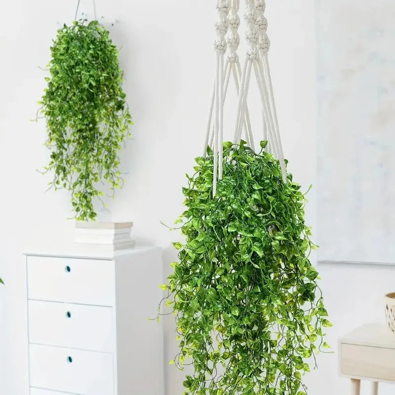Una exuberante planta colgante artificial de color verde junto a un mueble blanco