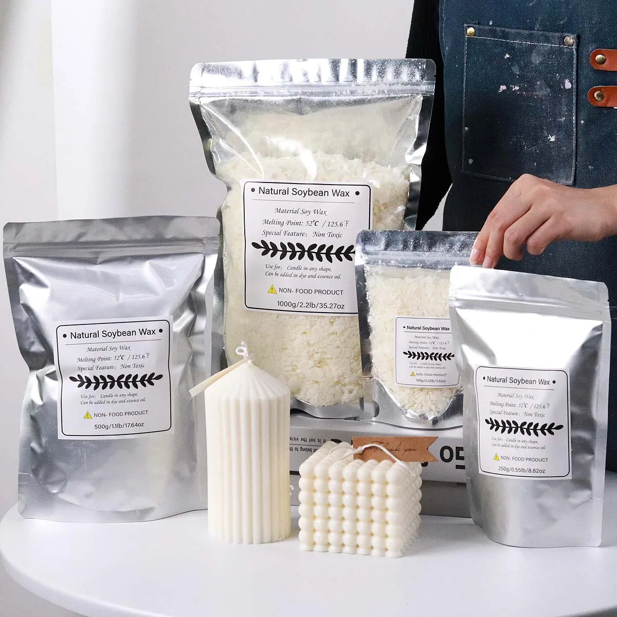 Verpackte natürliche Sojawachsflocken und eine fertige Kerze in einem weißen Halter