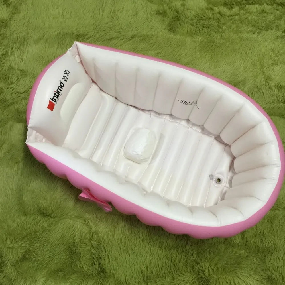 A pink inflatable bath tub for kids lying on a green textured surface.