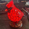 A bright red resin bird sculpture perched on a dark wooden base.