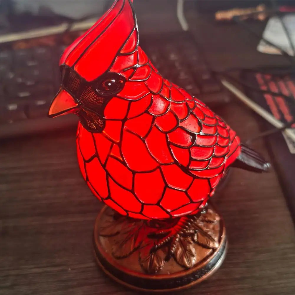 A bright red resin bird sculpture perched on a dark wooden base.
