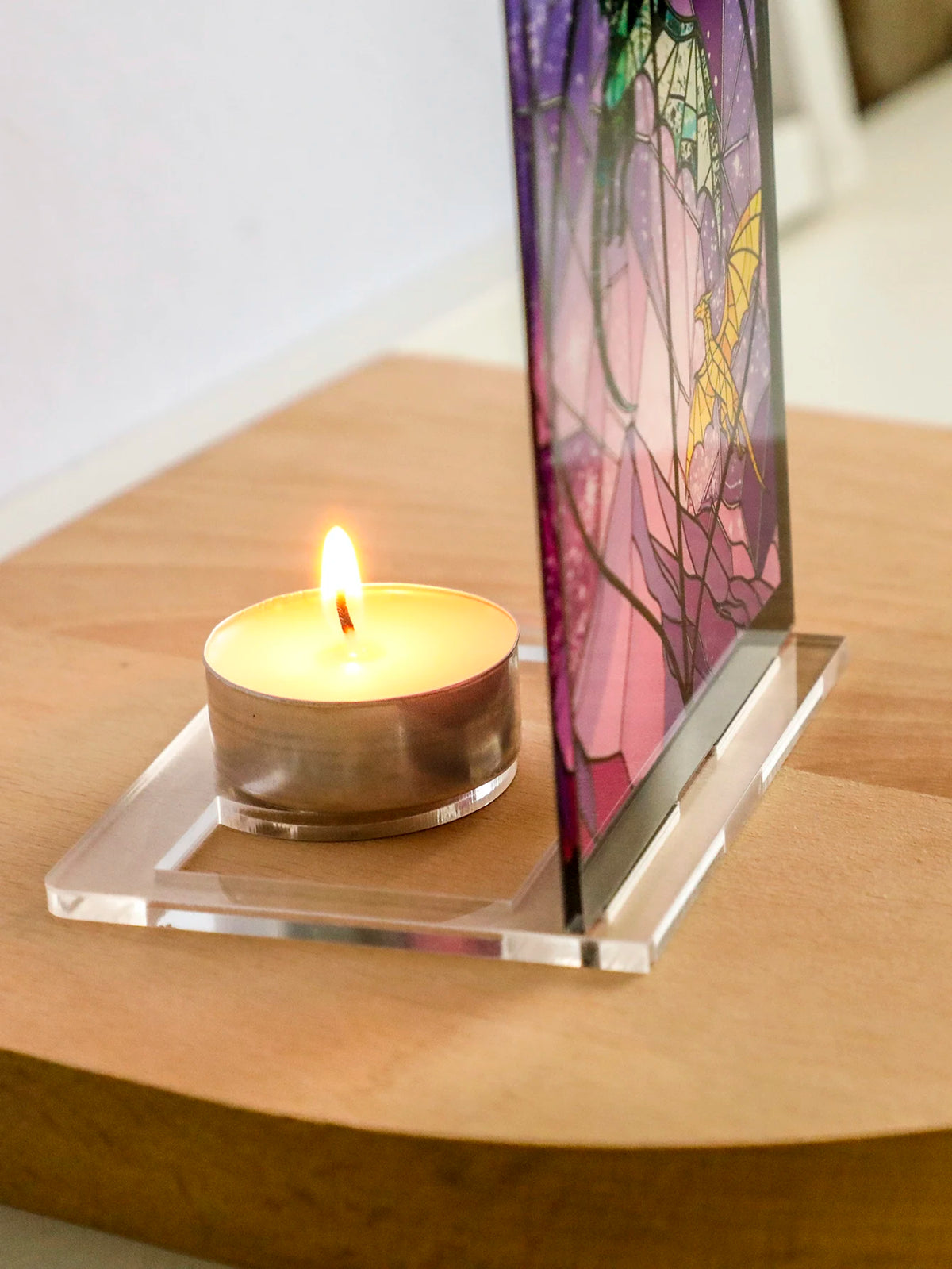 Porta-velas de dragón de arco gótico con una vela encendida sobre una superficie de madera.