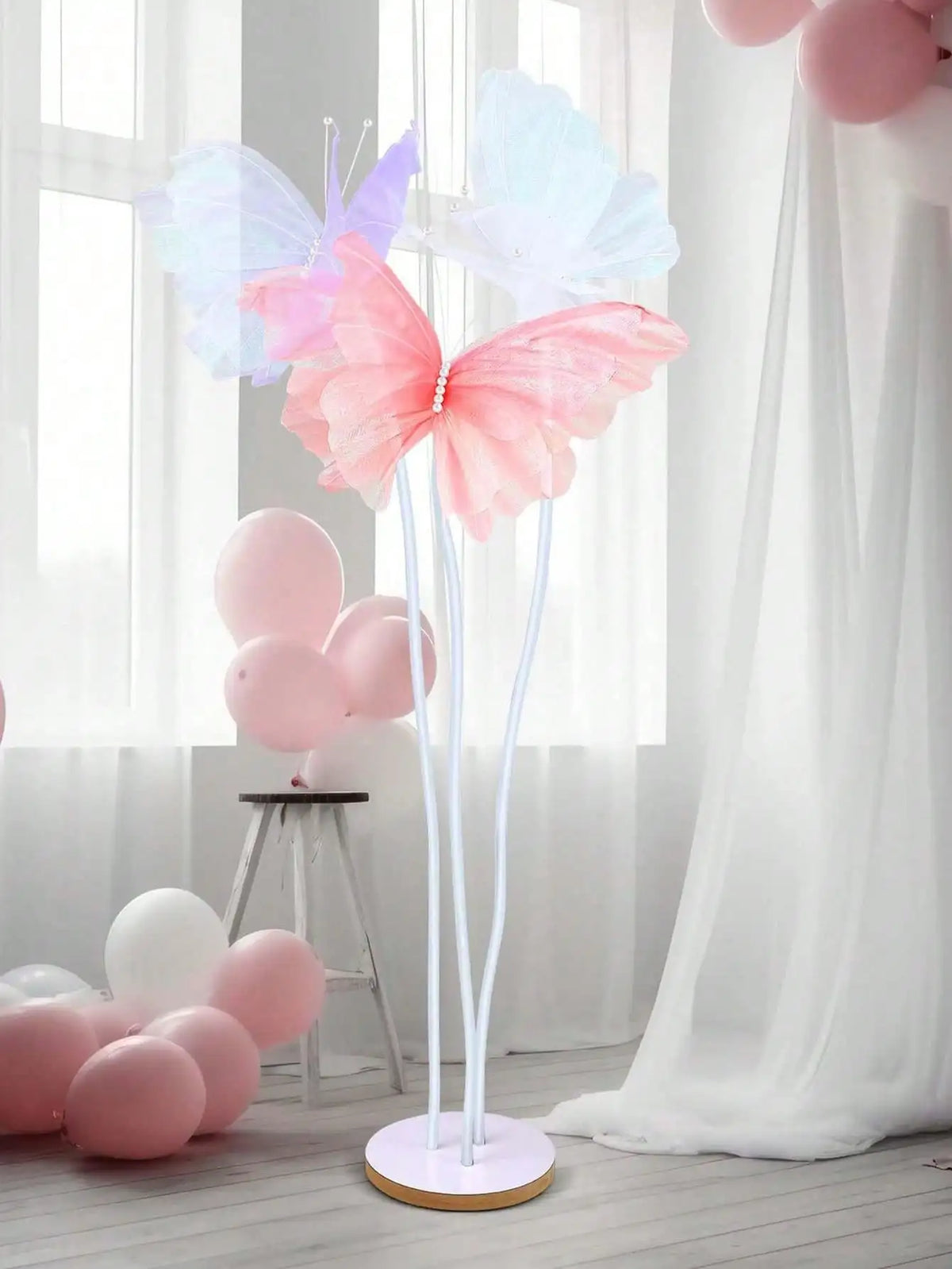 Pink and purple 3D simulated butterfly decorations with balloons in a white draped setting