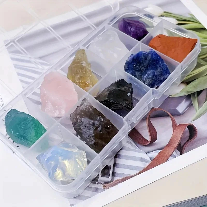 A clear plastic container holds various natural crystal stones in shades of purple, blue, green, and orange.
