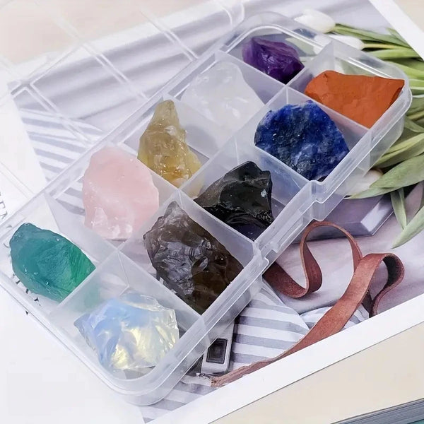 A clear plastic container holds various natural crystal stones in shades of purple, blue, green, and orange.