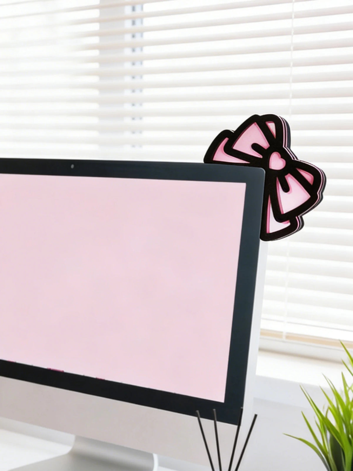 Un nœud rose en forme d'oreille de chat décoratif est placé à côté d'un moniteur d'ordinateur.