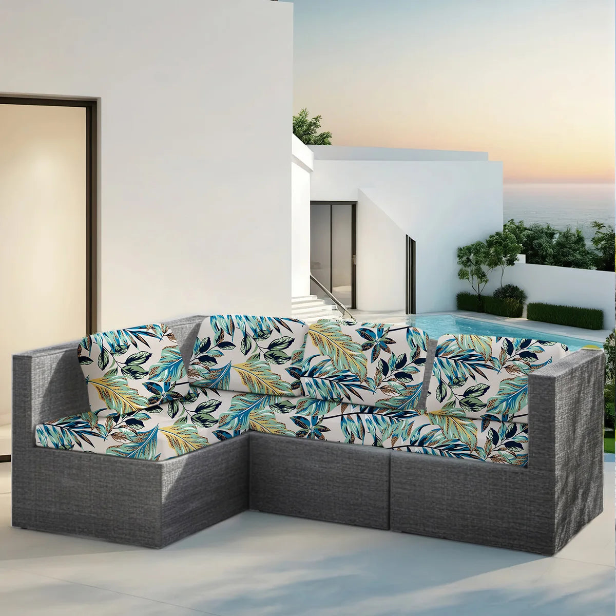 Fundas grises para sofá exterior con estampado de hoja tropical, colocadas en un patio cerca de una piscina.