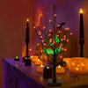Dekorativer Birkenbaumleuchte mit orange- und violetten LED-Lichtern auf einem Tisch mit Kerzen.