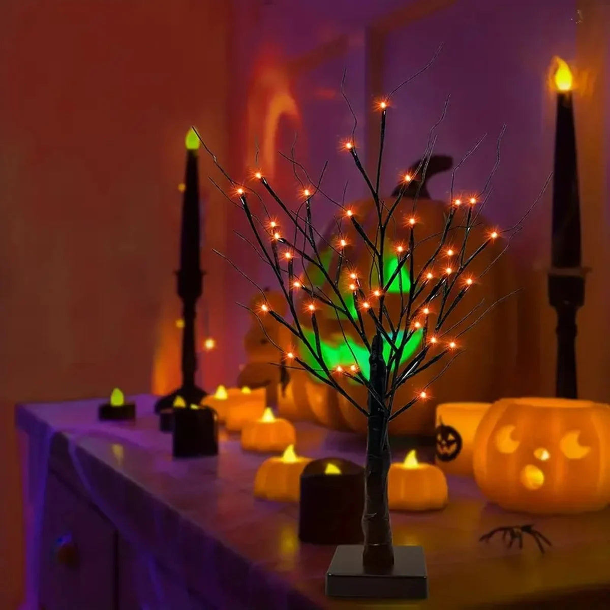 Dekorativer Birkenbaumleuchte mit orange- und violetten LED-Lichtern auf einem Tisch mit Kerzen.